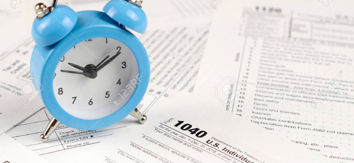 1040 Individual income tax return form and blue alarm clock